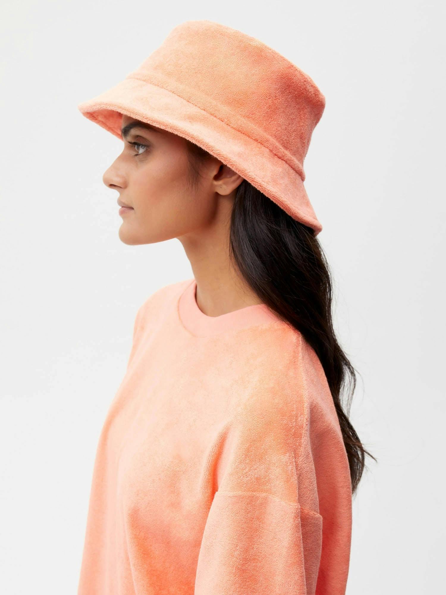 https://cdn.shopify.com/s/files/1/0035/1309/0115/products/Towelling-Bucket-Hat-Peach-Perfect-Female-1.jpg?v=1662476480